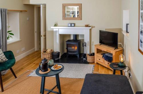 a living room with a fireplace and a tv at Kirk Wynd Cottage in Kirriemuir