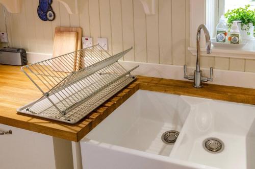 a kitchen sink with a strainer on top of it at Kirk Wynd Cottage in Kirriemuir