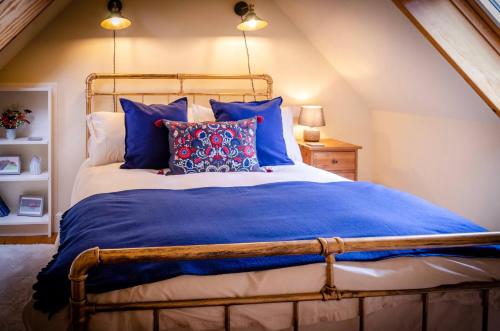 a bedroom with a large bed with blue pillows at Kirk Wynd Cottage in Kirriemuir