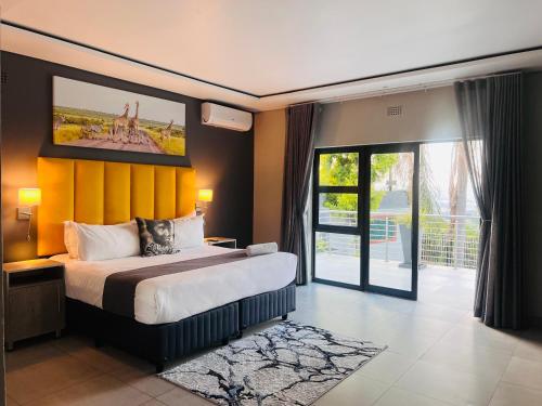 a bedroom with a large bed with a yellow wall at Khayalami Hotel - Mbombela in Nelspruit