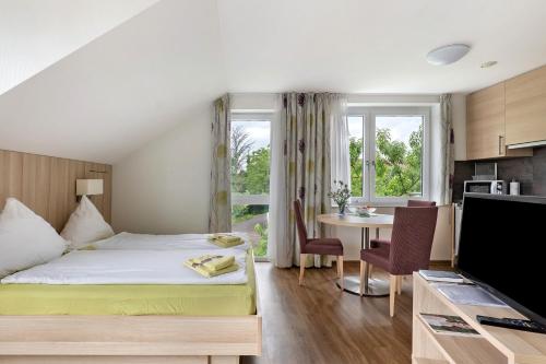 a bedroom with a bed and a table and a kitchen at Landpension Wachtkopf in Vaihingen an der Enz