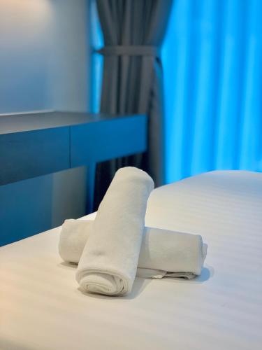 two rolls of white towels sitting on a bed at Eaton Residences By Classic in Kuala Lumpur