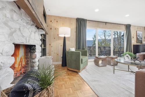 a living room with a stone fireplace and a green chair at Mtn Views, Game Room, Pet Friendly! in Seven Devils