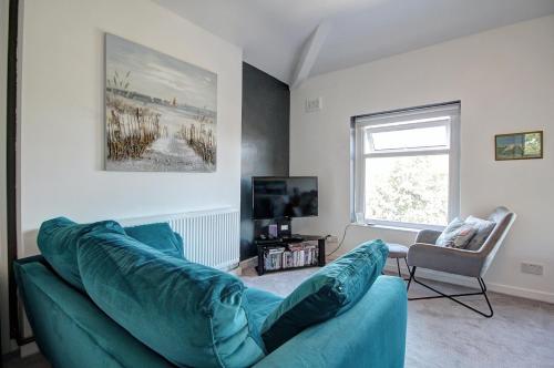 a living room with a blue couch and a window at Quaint Studio Apartment Near To Waterfront in Wallasey