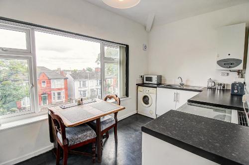 a kitchen with a table and a sink and a window at Quaint Studio Apartment Near To Waterfront in Wallasey