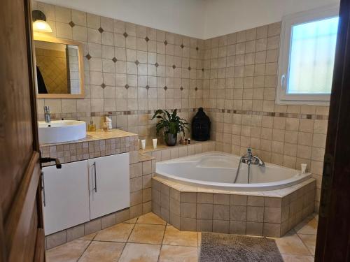La salle de bains est pourvue d'une grande baignoire et d'un lavabo. dans l'établissement Ideal Provencal family home, à Villetelle