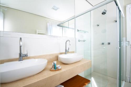 a bathroom with two sinks and a shower at Hotel Chateau in Campos do Jordão