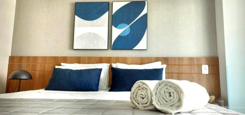 a bedroom with three pictures above a bed with blue pillows at Confortável Flat em Brasília-BR in Brasília