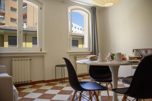 ein Esszimmer mit Tisch und Stühlen und zwei Fenstern in der Unterkunft T'Amo suite in Ravenna