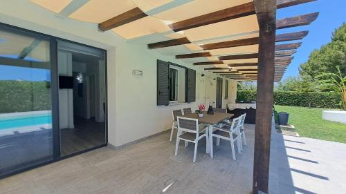 a patio with a table and chairs under a pergola at Villa Elios Adriana with pool by Casa in mente in Lascari