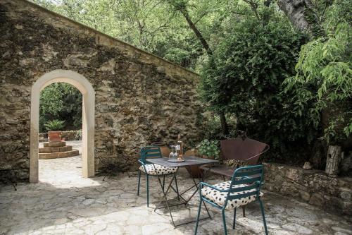 a table and chairs in front of a stone wall at Beautiful duplex apartment in a farmhouse in Provence Verte VAR in Bras