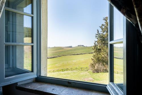 an open window with a view of a green field at Chianti Classico Wine Resort Tenuta di Bibbiano - I Sodi in Castellina in Chianti