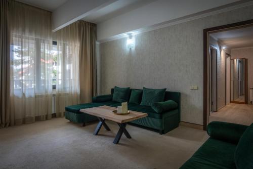 a living room with a green couch and a table at Snezhanka Hotel Pamporovo-All inclusive & Half Board in Pamporovo