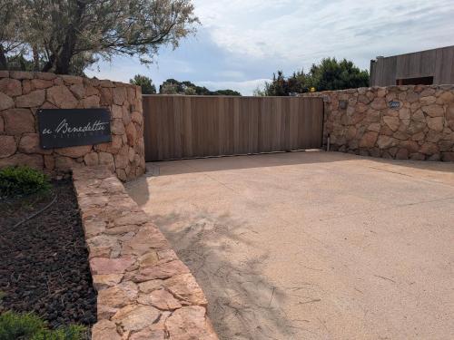 un mur de soutènement en pierre avec une clôture dans une cour dans l'établissement Les maisons de Benedettu, à Lecci