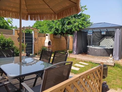 a table and chairs under an umbrella in a yard at Le Petit Marais in Échiré
