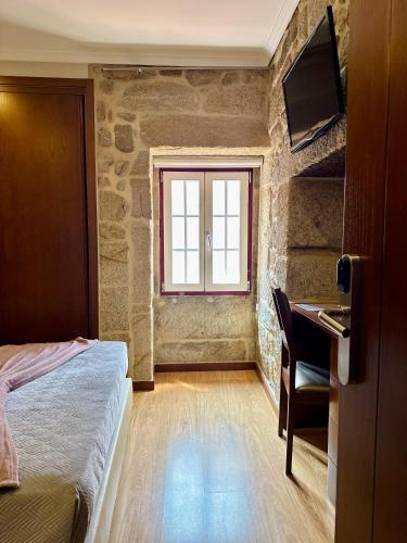 a bedroom with a bed and a desk and a window at Alojamento Central in Chaves