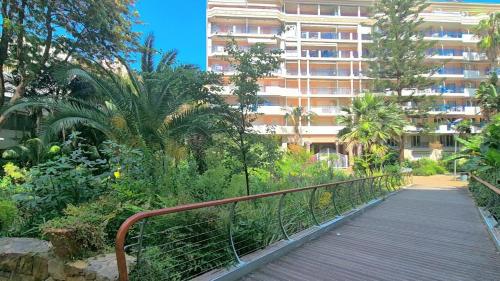 une passerelle devant un grand bâtiment avec des arbres dans l'établissement Casa GAIA, à Menton