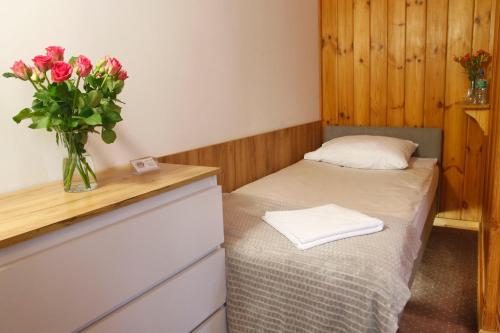 a small room with a bed and a vase of roses at Willa 1910 in Karpacz