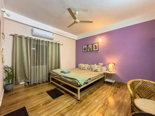 a bedroom with a bed and a purple wall at Thikana by Mulaqat in Siliguri