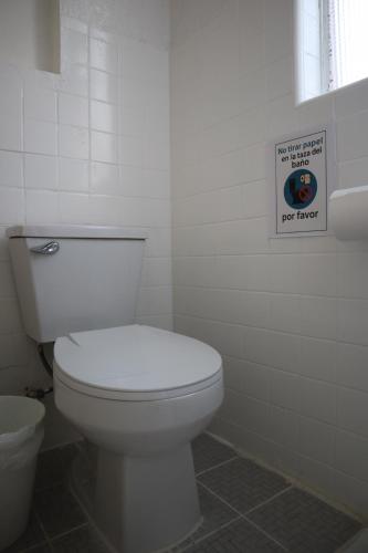 a bathroom with a toilet and a sign on the wall at Casa Artemisa hostal in Guadalajara