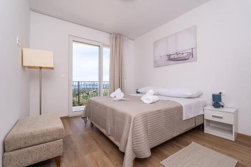 a white bedroom with a bed and a window at Villa Leona in Dubrovnik
