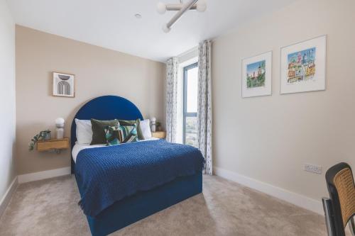 a bedroom with a blue bed and a window at Stunning Premium 2 Bed Flat with Great Views - Rooftop on Top Floor in Croydon