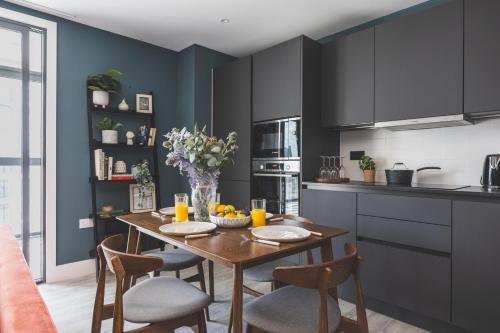 a kitchen with a wooden table with chairs and a table at Stunning Premium 2 Bed Flat with Great Views - Rooftop on Top Floor in Croydon