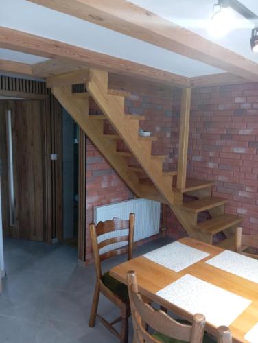 a wooden table and a brick wall with a wooden stairs at Domek letniskowy in Klusek Biały