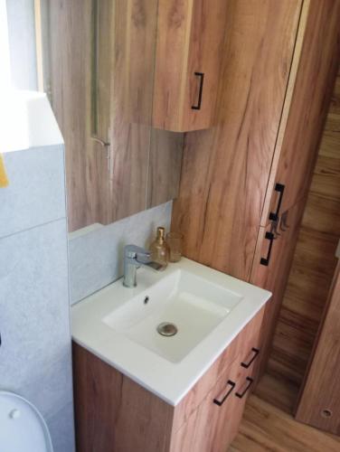 a bathroom with a white sink and a wooden wall at Domek letniskowy in Klusek Biały