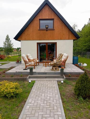 a house with rocking chairs and a basketball hoop at Domek letniskowy in Klusek Biały