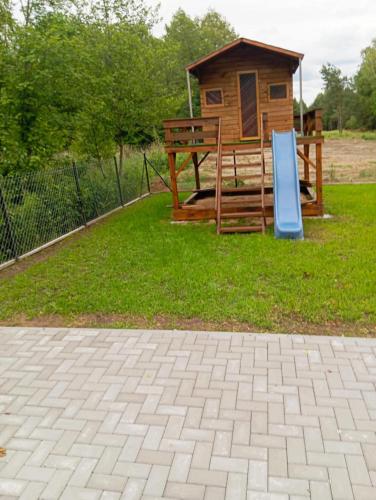 a wooden cabin with a sign in the grass at Domek letniskowy in Klusek Biały