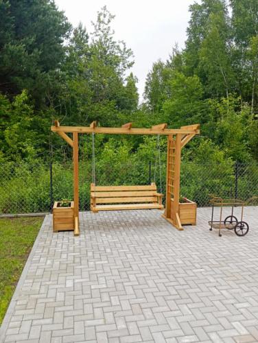 a wooden bench with a swing in a park at Domek letniskowy in Klusek Biały