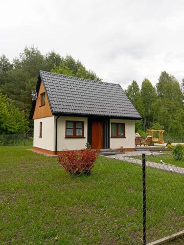 a small house in a yard with a fence at Domek letniskowy in Klusek Biały