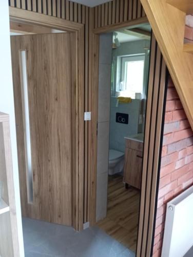 a bathroom with wooden doors and a toilet in a room at Domek letniskowy in Klusek Biały