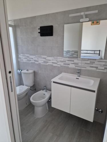 a bathroom with a sink and a toilet and a mirror at Appartamento denilu in Cittadella del Capo
