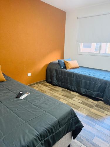 a room with two beds and an orange wall at Departamento en vicente López hasta 3 personas súper comodo in Florida