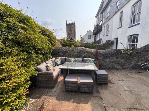 eine Terrasse mit einem Sofa, einem Tisch und einem Gebäude in der Unterkunft Saviours View in Dartmouth