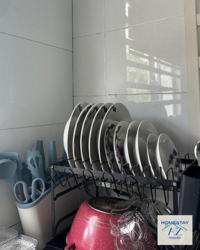 a bunch of dishes on a shelf in a kitchen at Homestay AZ Kulim in Kulim