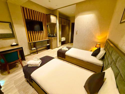 a hotel room with two beds and a flat screen tv at Heaven Hotel Tashkent in Yakkasaray