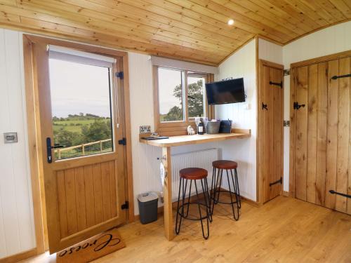 a small kitchen with two stools in a tiny house at Defaid Cymreig in Oswestry
