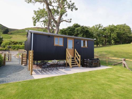 a tiny house with a patio and a grill at Defaid Cymreig in Oswestry