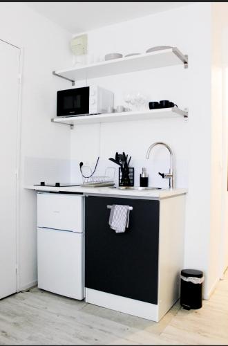 - une cuisine avec un comptoir noir et blanc et un évier dans l'établissement Studio-parking-wifi-Disney-Val d'Europe 10 mn, à Montévrain