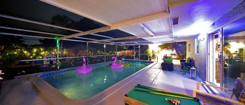 a swimming pool with pink swans in the water at night at Villa Ft Lauderdale XL Pool, playground, BBQ, beach, Family Paradise in Fort Lauderdale