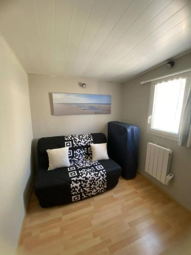 un salon avec un canapé noir dans une pièce dans l'établissement Maison Familiale en bord de plage, à Lacanau