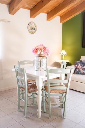 a white dining room table with chairs and a vase of flowers at Residence Cà di Capri in Bussolengo