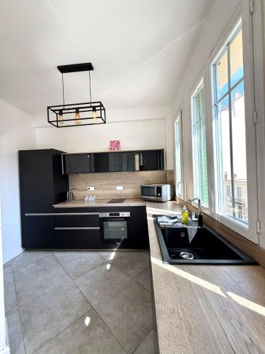 une grande cuisine avec des placards noirs et un évier dans l'établissement Appartement proche palais, à Cannes