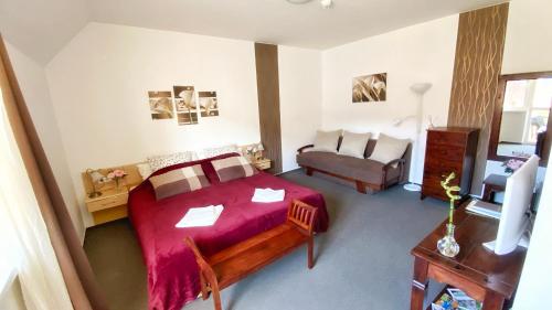 a bedroom with a red bed and a couch at Kala Thermal Lake Wellness Apartment in Zalakaros