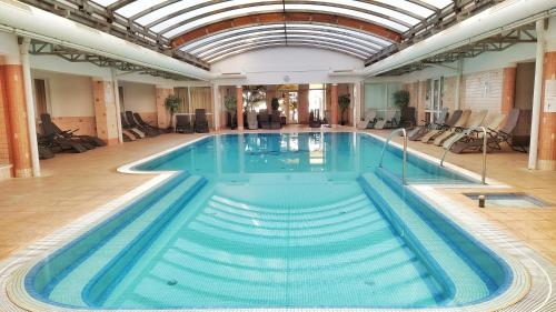 a large swimming pool in a building with a ceiling at Kala Thermal Lake Wellness Apartment in Zalakaros