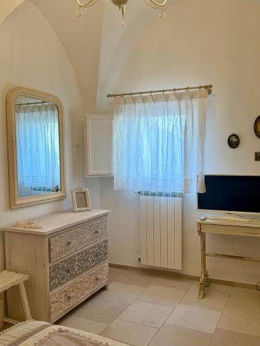a bedroom with a dresser and a mirror and a window at Dimora Orsini del Balzo in Carovigno