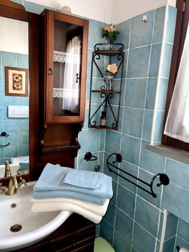 a blue tiled bathroom with a sink and a mirror at VillAmato Casa Vacanze ULIVO in Arezzo